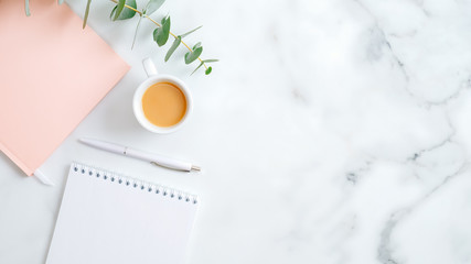 Wedding planner, cup of coffee, pink notebook, pen, eucalyptus leaf on marble desk. Flat lay, top...