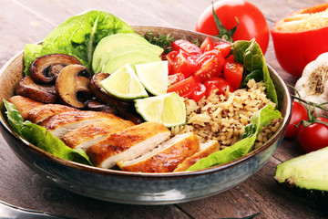 Healthy salad bowl with quinoa, tomatoes, chicken, avocado, lime and mixed greens and mushrooms