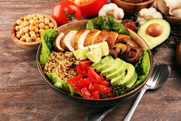 Healthy salad bowl with quinoa, tomatoes, chicken, avocado, lime and mixed greens and mushrooms