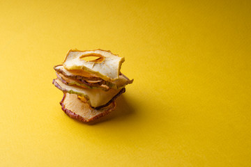 Pyramid of chips of dried apples on a yellow background and a place for inscription. Copyspace.