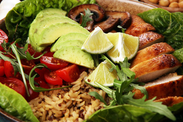 Healthy salad bowl with quinoa, tomatoes, chicken, avocado, lime and mixed greens and mushrooms
