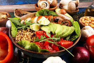 Healthy salad bowl with quinoa, tomatoes, chicken, avocado, lime and mixed greens and mushrooms
