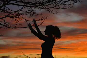 Hippie girl doing a ritual with a tree during a sunset. Hippie spirituality concept, mother earth  