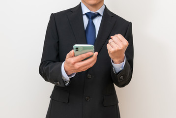 スマホを見てガッツポーズする男性