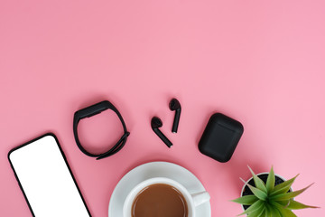 Flat lay  listen to music and sing song concept on pink table desk background with blank screen phone and earphone , coffee cup and leave, Top view with copy space