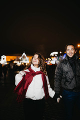 Loving couple walks in the evening in the winter city on a date, night lights.