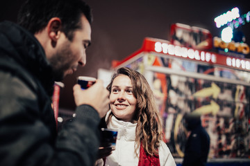 couple in love in the evening in the winter in the city drinking drinks and walking among the lights and attractions.