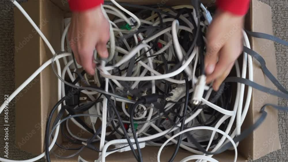 Poster top view of hands successfully untangling one electronics cord from many in a box