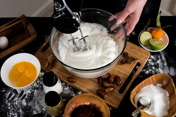 Hands beating egg whites cream with mixer in the bowl.