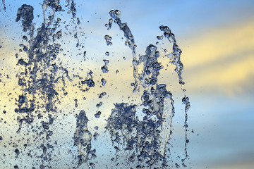 Drops of a falling water fountain against the evening sky. natural textures and backgrounds