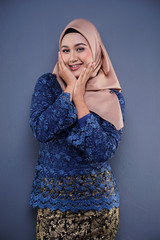 Attractive female Muslim model wearing dark blue modern kurung with hijab, a modern urban lifestyle apparel for Muslim women isolated on grey background. Beauty and hijab fashion concept.