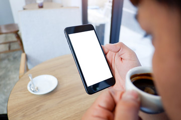 Mockup picture of business man's hands or woman’s hands holding smart phone with white blank screen in modern place.