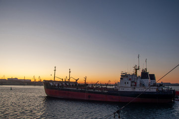 Fototapeta premium A large old ship with pipes on the deck is empty in the creek of the sea at sunset.