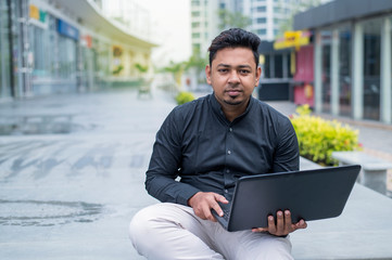 Young entrepreneur or Businessman working on laptop outside the office building.