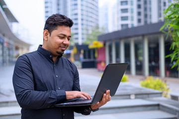 Young entrepreneur or Businessman working on laptop outside the office building.