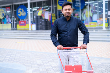 Man pushing shopping trolley outside the supermarket in India, shopping concept 