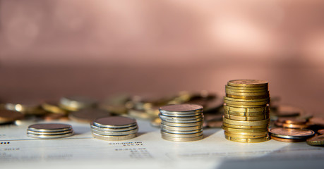 Stacks of coins piled on top of a bank statement, pile of money in the back, pink background, money growth concept banner