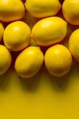 Top view many ripe lemons on a yellow surface, background or concept
