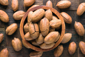 shelled pecan nuts fried with cocoa butter in wooden bowl, top view.