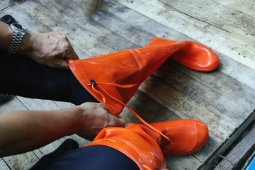 A man wearing orange rubber waterproof bootes