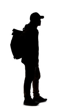 Silhouette of a man hiking and carrying a backpack on a white background.  The isolated side view man can be used for composites.  Depicts adventure and exploration.