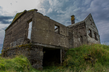 Obraz premium View of the old destroyed house from its back. The foundation and the remains of the roof in the grass