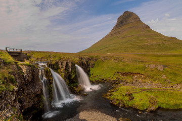 Panoramic view of three waterfalls on the background of a lonely pointed mountain in the form of an arrowhead