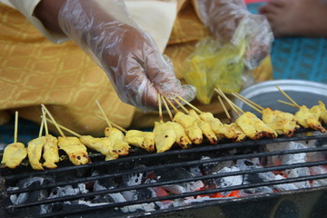 Chicken Satay sticks are grilling on traditional roaster and fire from charcoal, Thailand.