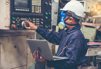 Chemical engineers wear helmet hat, and put chemical-resistant masks, carry laptops, inspect and control chemicals in the factory.