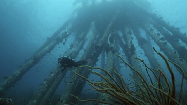 Scuba diver at huge underwater pylone structure, Bonaire