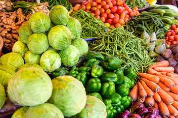 Abundance of vegetables in Asian street market. Heaps of various vegetables at bazaar in India, close up. Cabbage, carrots, eggplant, tomatoes, green paprika string beans.
