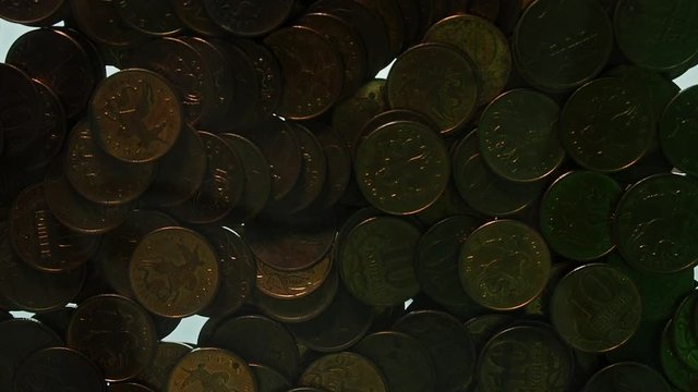 View from below as the hand throws gold coins. Moves them, collects them in the shape of a heart or columns.White background. Indoors.