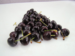 Fresh cherries with drops arranged in triangles on a white background