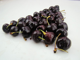 Fresh cherries with drops arranged in triangles on a white background
