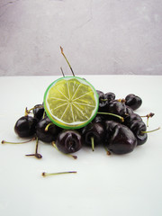 Pile of cherry and lemon slices with ice cubes on white background