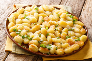 oil-fried potato dumplings gnocchi with garlic, cheese and green onions close-up on a plate on the table. horizontal
