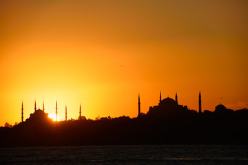 Fototapeta na wymiar Sun setting behind Blue Mosque with Hagia Sophia in silhouette on the Bosphorus Istanbul