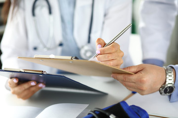 Two GP examining test results clipped to pad closeu-up