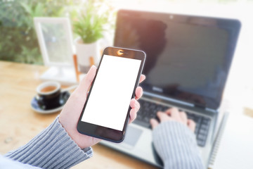 Mockup picture of business woman’s hands or man's hands holding smart phone with white blank screen in modern place.