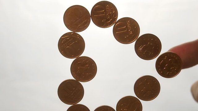 View from below as the hand throws gold coins. Moves them, collects them in the shape of a heart or columns.White background. Indoors.