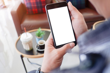 Mockup picture of business woman’s hands or man's hands holding smart phone with white blank screen in modern place.