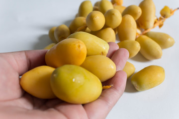 Raw yellow dates on woman hand. Selective focus.