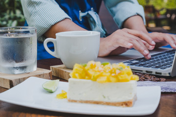 Business women using laptop after drinking coffee and eat cake