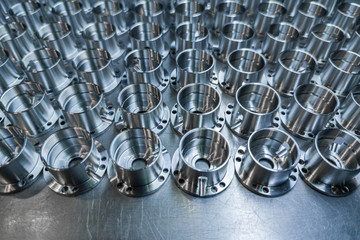 a batch of shiny metal cnc aerospace parts production - close-up with selective focus for...