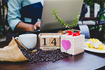 14 February wooden calendar in Valentine day with Business women using laptop and drinking coffee