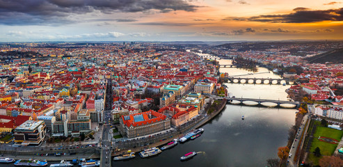Obraz premium Prague, Czech Republic - Aerial panoramic drone view of city of Prague at dusk. Red rooftops, the famous Charles Bridge (Karluv most) and St. Francis Of Assisi Church and magical winter sunset and sky