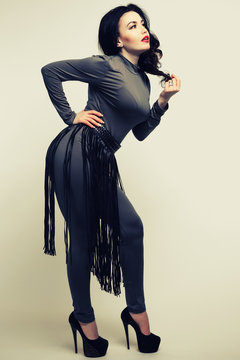 BDSM outfit fringe skirt on a woman in a gray fitted spandex jumpsuit. Fetish concept.