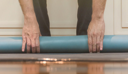 The man is using his hands to roll green yoga