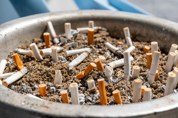 The big ashtray with many focus and blurred cigarettes