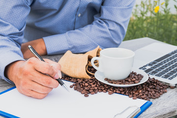 Businessman note the quality of coffee beans after drinking coffee and using tablet